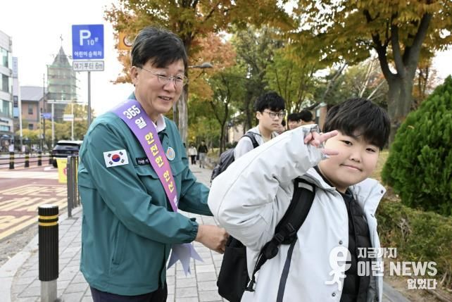 이민근 안산시장(사진 왼쪽)이 학현초등학교 앞에서 ‘스쿨존 어린이 교통안전 캠페인’을 진행하며 등교하는 어린이의 가방에 '홍이 키링'을 달아주고 있다.